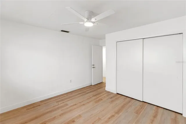 an empty room with wooden floor and fan