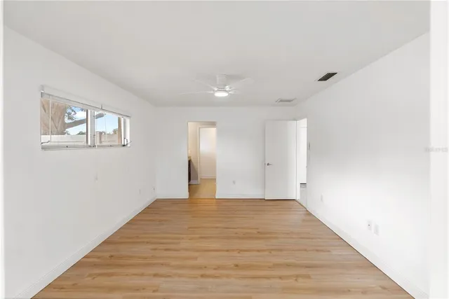 a view of an empty room with wooden floor and a window