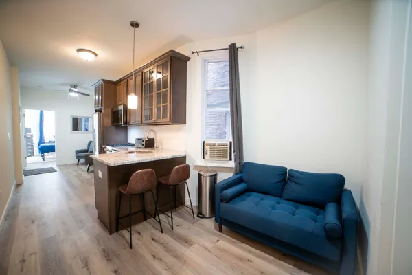 a living room with stainless steel appliances kitchen island granite countertop furniture and a wooden floor