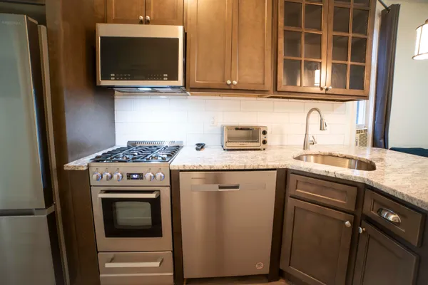 a kitchen with stainless steel appliances granite countertop a stove microwave and sink
