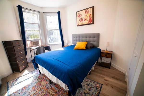 a bedroom with a bed and a dresser next to a window