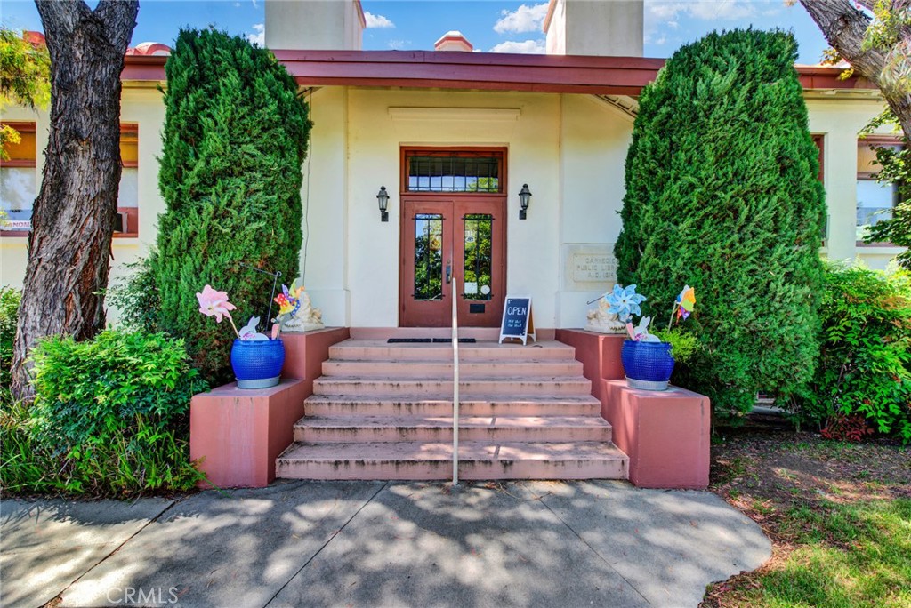 a view of a house with potted plants and a bench