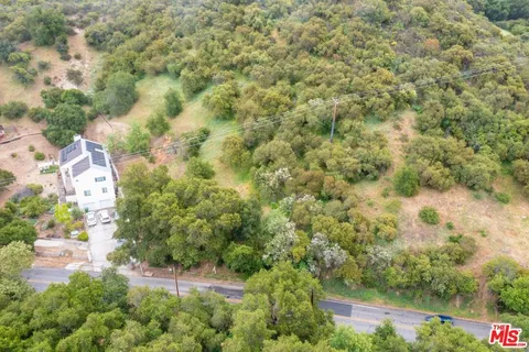 an aerial view of residential house with outdoor space and trees all around