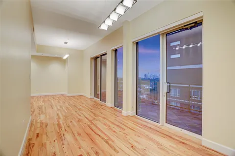 a view of empty room with wooden floor and fan