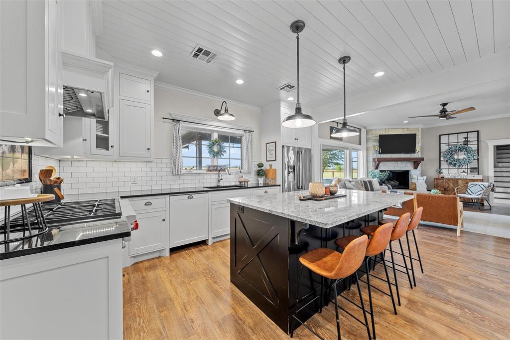 2045 Iron Bridge Road Lorena, TX 76655 - Photo 11 of 40 a kitchen with stainless steel appliances kitchen island granite countertop a stove a sink a dining table and chairs with wooden floor