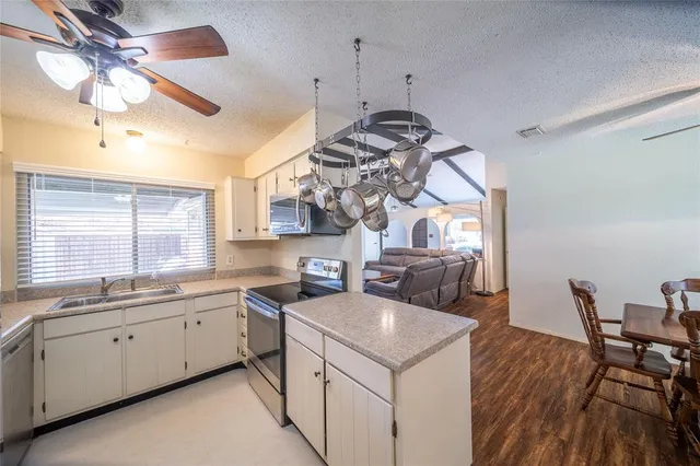 a kitchen that has a sink a stove and chairs with wooden floor