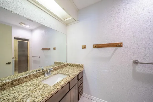 a bathroom with a granite countertop sink and a mirror