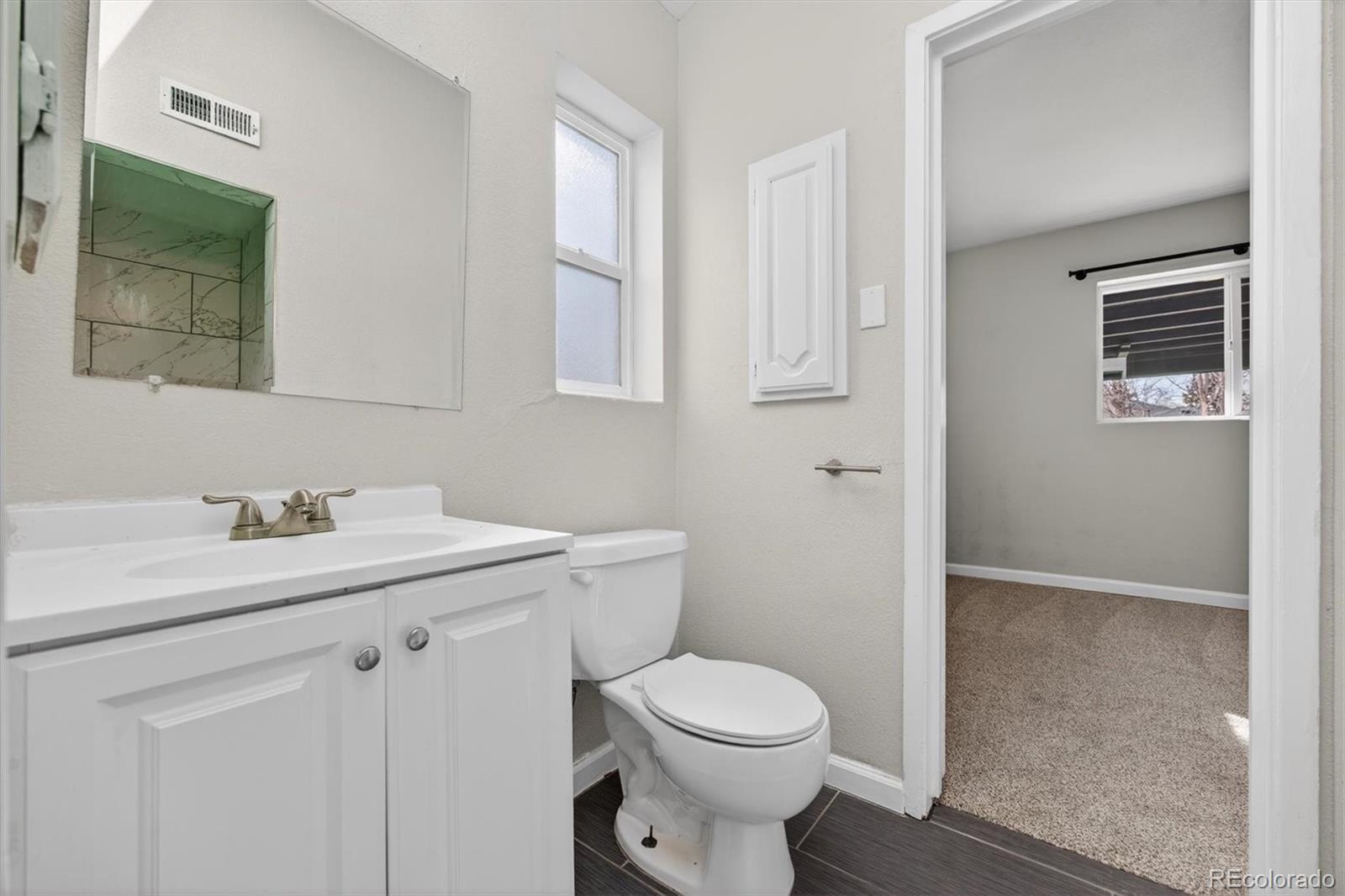 901 Racine Street Aurora, CO 80011 - Photo 14 of 29 a bathroom with a toilet a sink a vanity and mirror