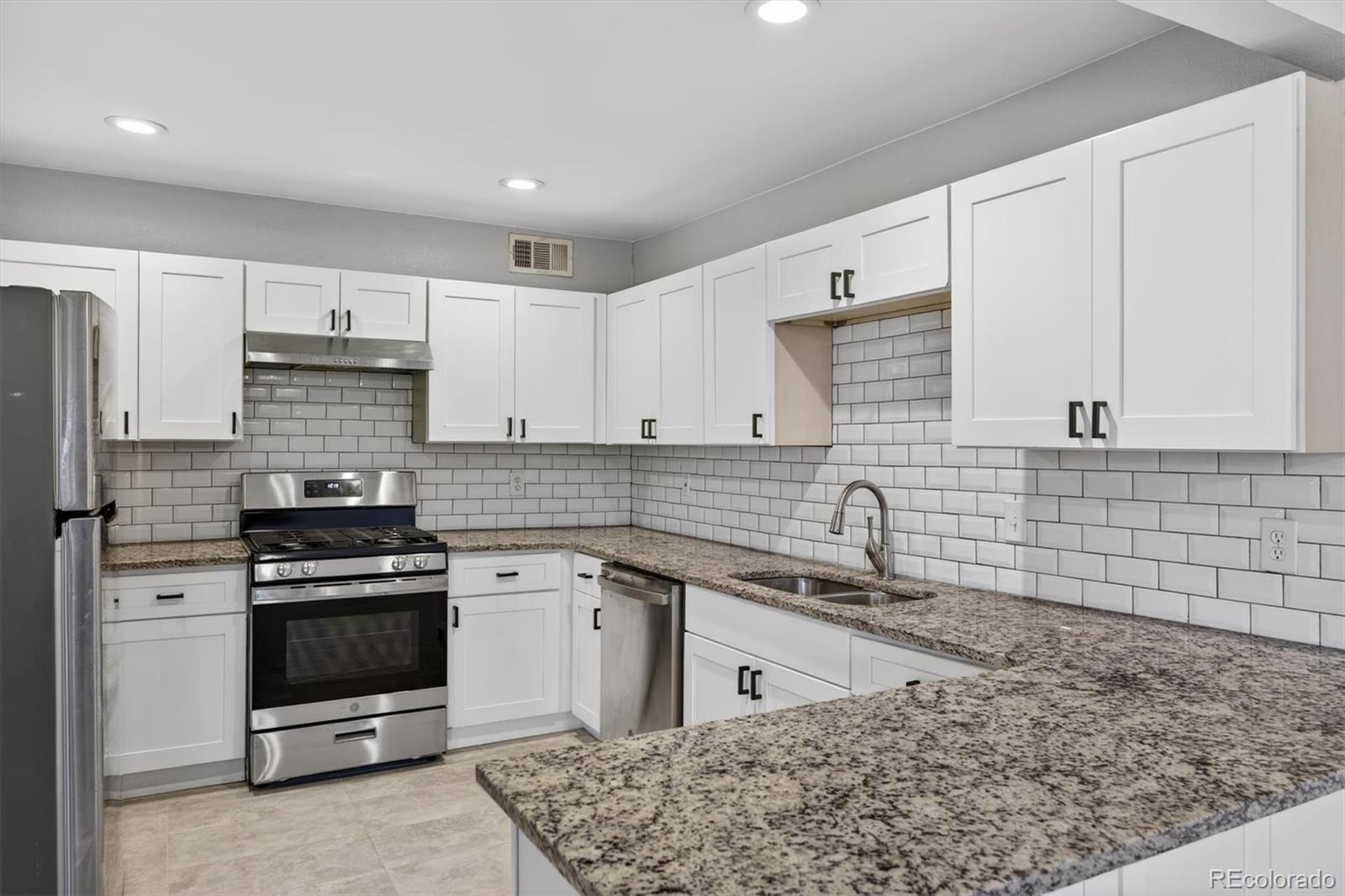 901 Racine Street Aurora, CO 80011 - Photo 7 of 29 a kitchen with stainless steel appliances granite countertop a stove and a sink