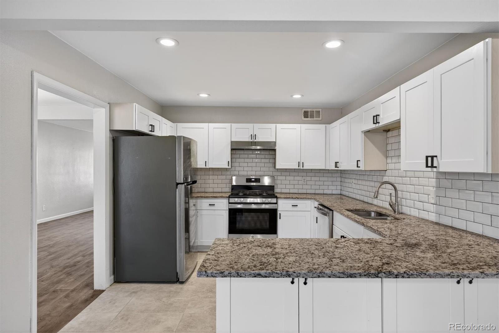 901 Racine Street Aurora, CO 80011 - Photo 8 of 29 a kitchen with stainless steel appliances granite countertop a sink stove and refrigerator