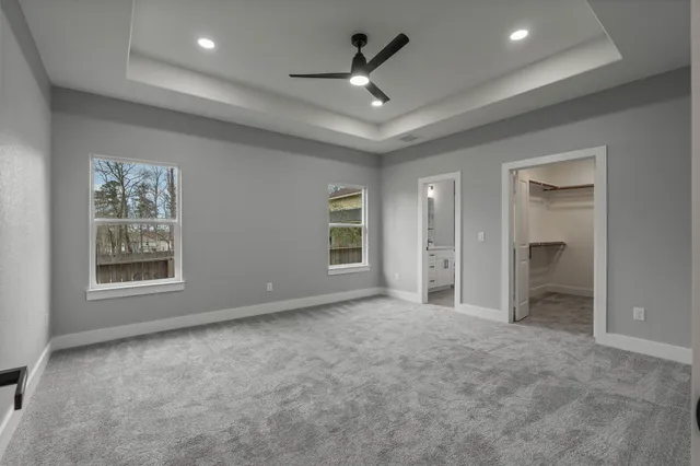 an empty room with windows and ceiling fan