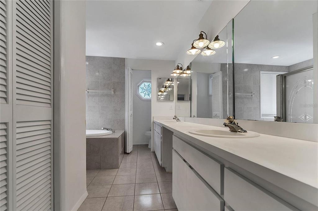 5607 Spring Run Avenue Orlando, FL 32819 - Photo 15 of 20 a bathroom with a sink a large mirror and a bathtub