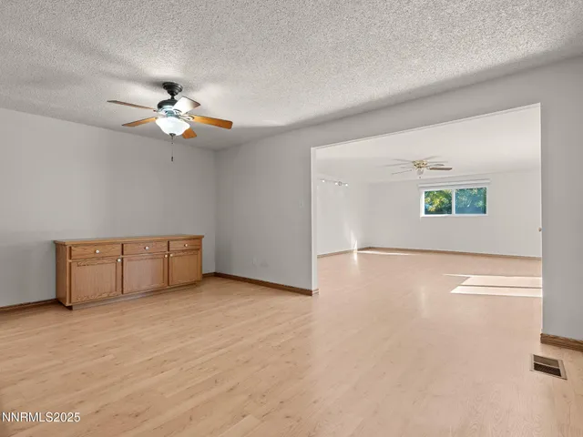 an empty room with windows and ceiling fan