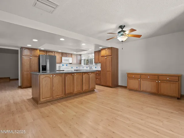 a view of kitchen with stainless steel appliances granite countertop a refrigerator and a stove top oven