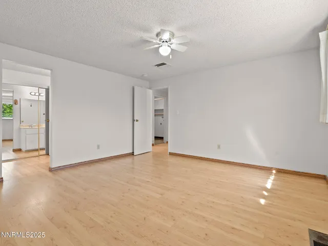 a view of an empty room with chandelier fan and wooden floor