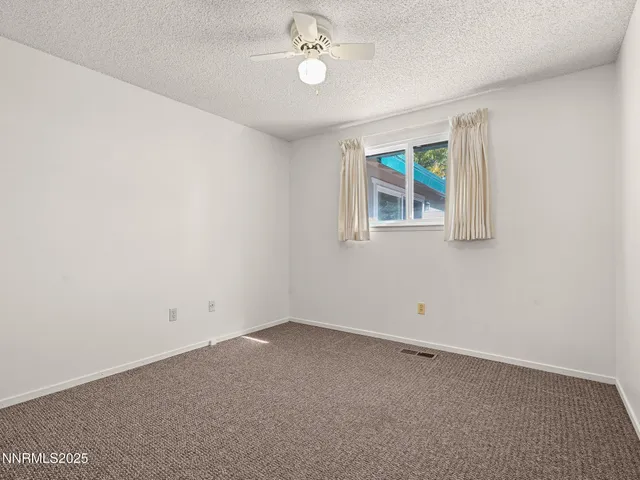 an empty room with a window and ceiling fan