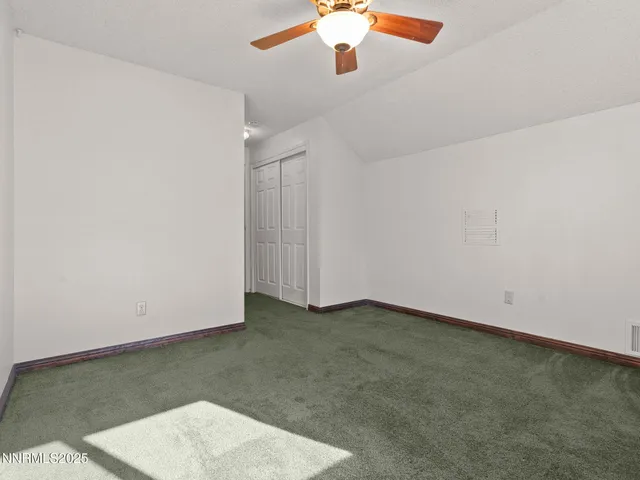 an empty room with a ceiling fan and carpet
