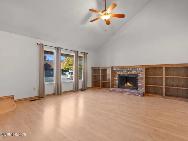 an empty room with windows fireplace and fans