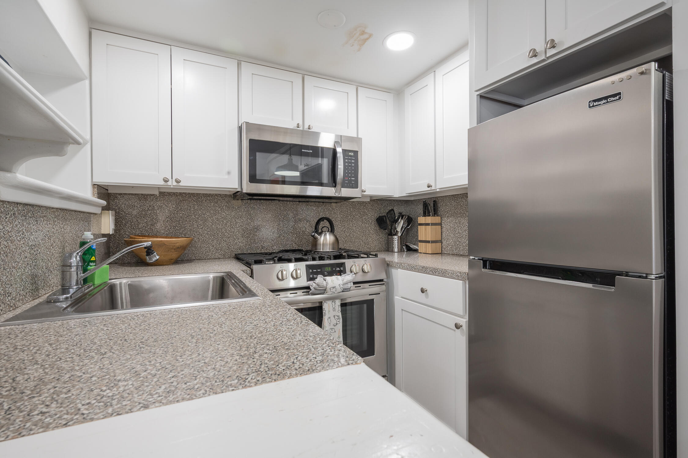 609 1/2 Margaret Street Key West, FL 33040 - Photo 4 of 35 a kitchen with white cabinets and stainless steel appliances
