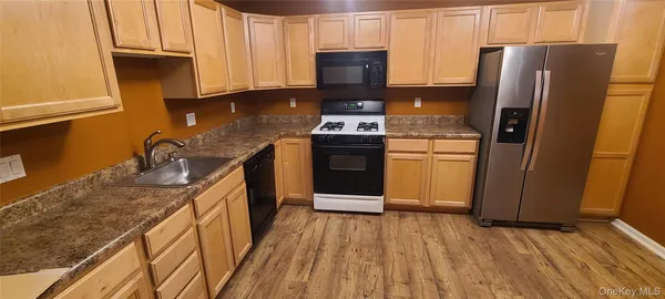 a kitchen with stainless steel appliances granite countertop a refrigerator a stove and a sink with wooden floors