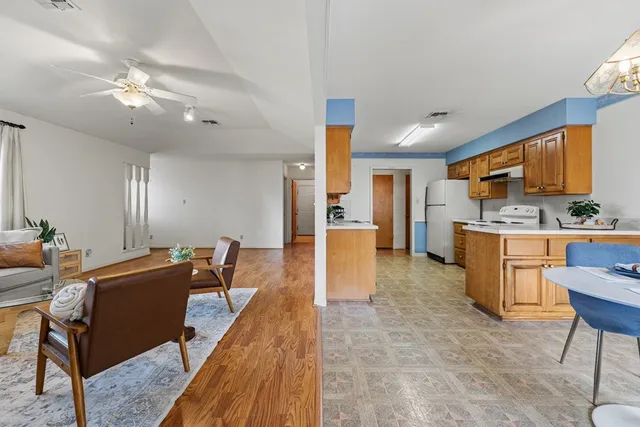 a view of a kitchen with kitchen island stainless steel appliances refrigerator stove dining table and chairs