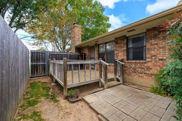 a view of a small house with wooden fence and trees