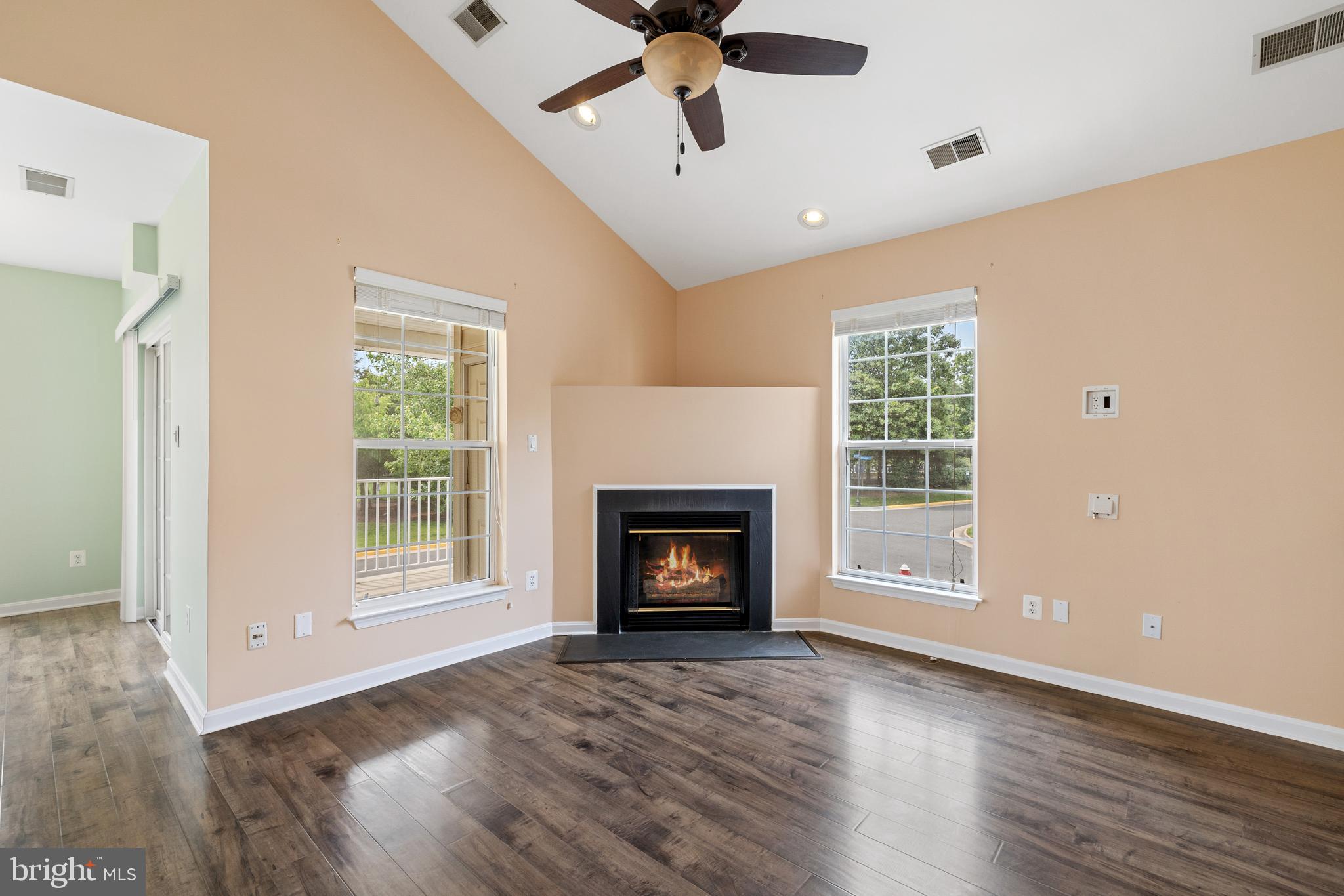 an empty room with windows fireplace and wooden floor