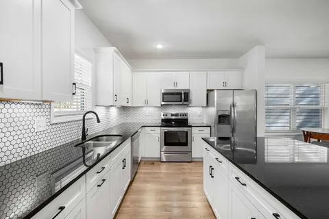 a kitchen with stainless steel appliances a sink stove refrigerator and cabinets