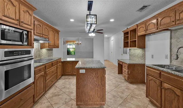 a kitchen with stainless steel appliances granite countertop a stove top oven microwave and cabinets
