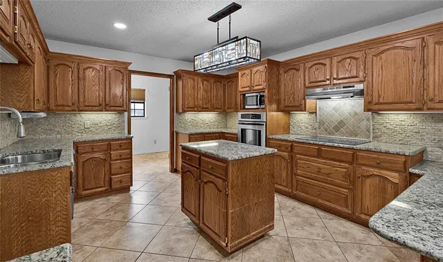a kitchen with stainless steel appliances granite countertop a stove a sink and a refrigerator