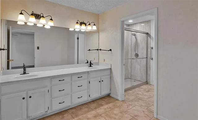 a spacious bathroom with double sink a mirror a vanity and a shower