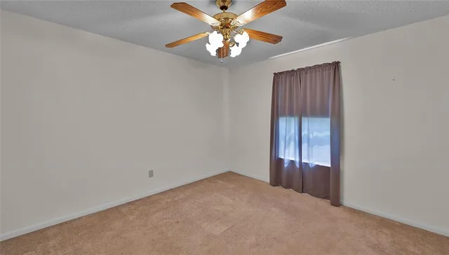 an empty room with a chandelier fan and windows