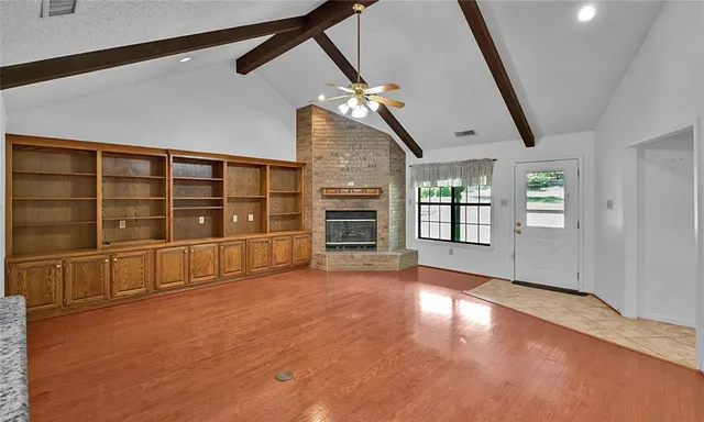 a view of an empty room with a window and wooden floor