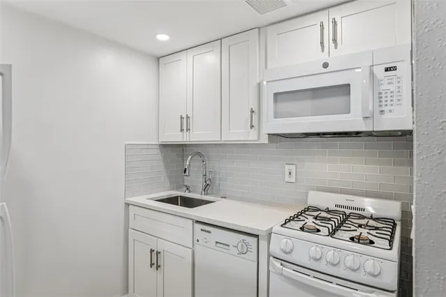 a kitchen with white cabinets and appliances