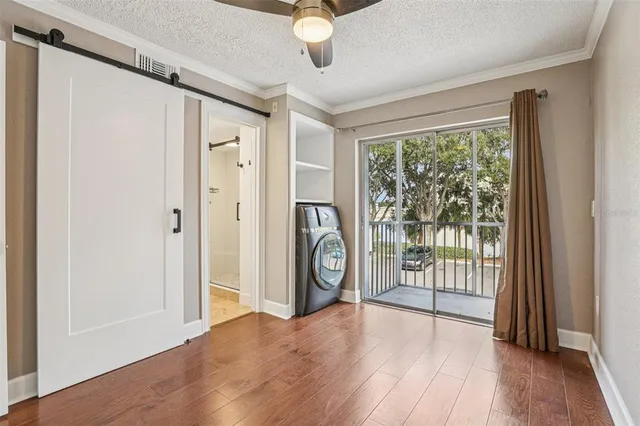 a view of empty room with wooden floor and fan