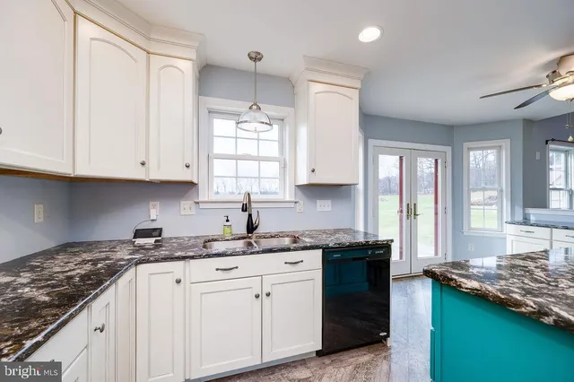 a kitchen with granite countertop a refrigerator a sink dishwasher and a stove with wooden floor