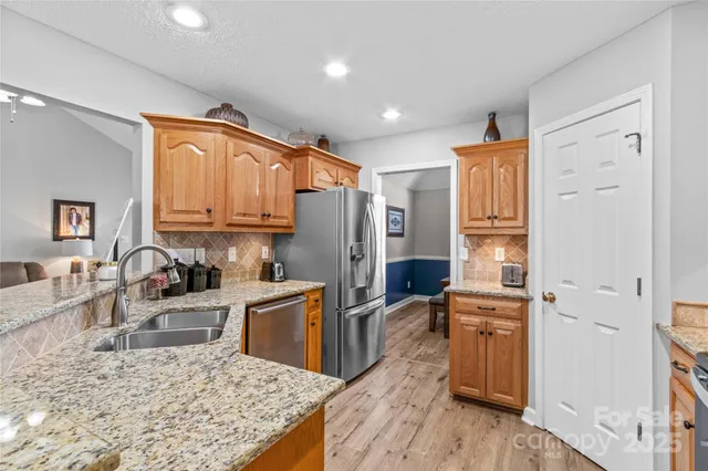a kitchen with stainless steel appliances granite countertop a refrigerator stove oven and sink