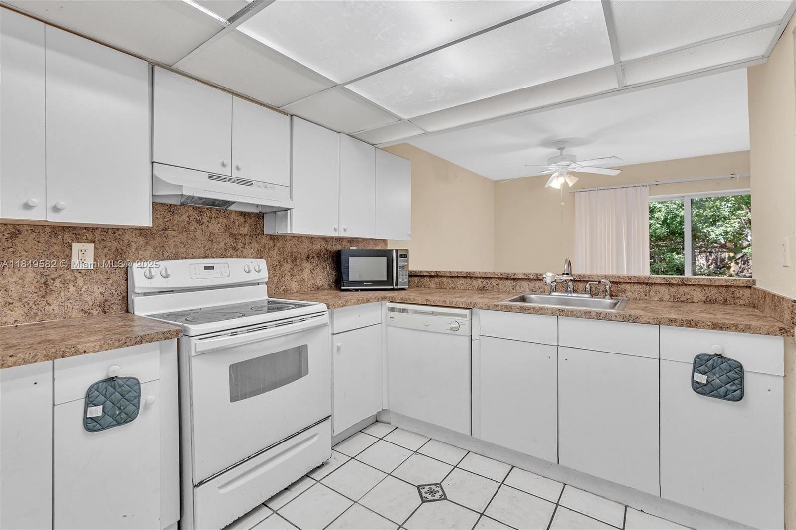 3750 Southwest 60th Terrace, Unit 1 Davie, FL 33314 - Photo 23 of 56 a kitchen with granite countertop white cabinets and white appliances