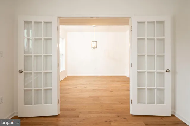 a view of an empty room with wooden floor and windows