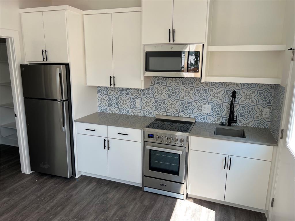 7603 Carver Avenue, Unit 2 Austin, TX 78752 - Photo 9 of 9 A stylish tiled backsplash complements modern cabinetry and durable stone countertops in this bright kitchen.