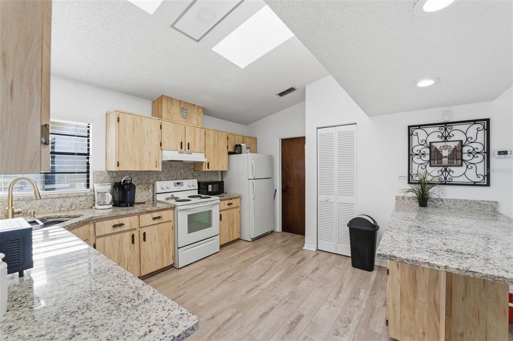 7822 Holiday Drive Spring Hill, FL 34606 - Photo 9 of 51 a kitchen with stainless steel appliances granite countertop a refrigerator a stove top oven a sink dishwasher and white cabinets with wooden floor