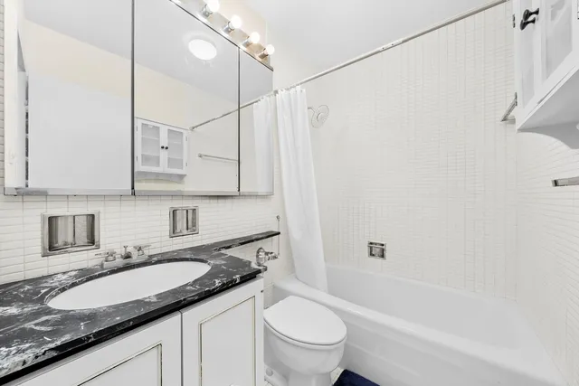 a bathroom with a granite countertop sink a toilet and shower