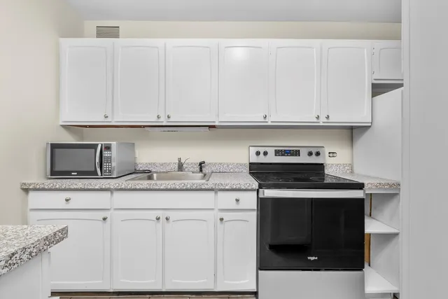 a kitchen with granite countertop white cabinets and a stove