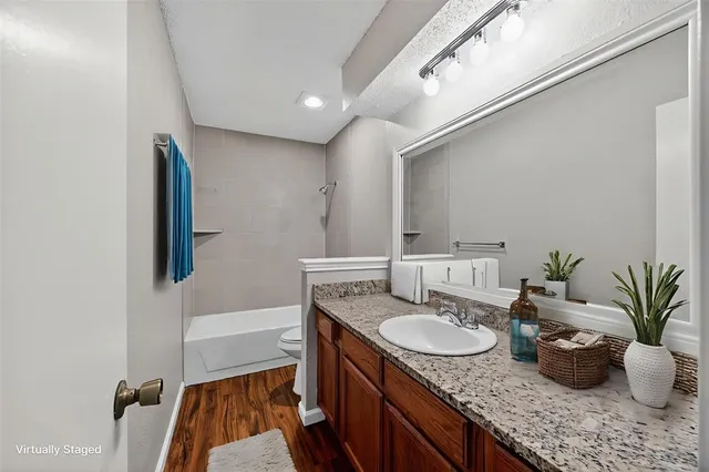 a bathroom with a granite countertop sink a mirror a vanity and a shower