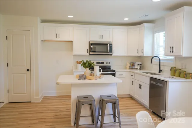 a kitchen with stainless steel appliances granite countertop a white cabinets and wooden floor