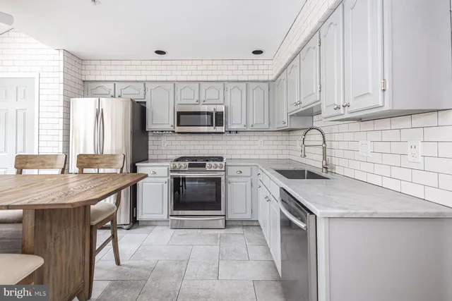 a kitchen with stainless steel appliances granite countertop a sink stove microwave and refrigerator