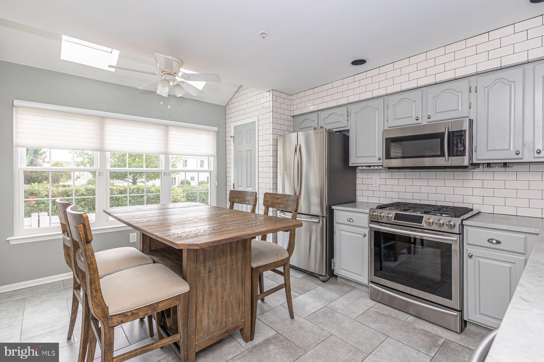 102 Waverly Lane, Unit 4 New Hope, PA 18938 - Photo 9 of 28 a kitchen with stainless steel appliances granite countertop a stove a sink dishwasher a dining table and chairs with wooden floor