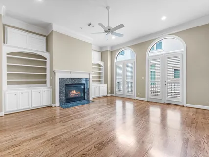 an empty room with wooden floor fireplace and windows