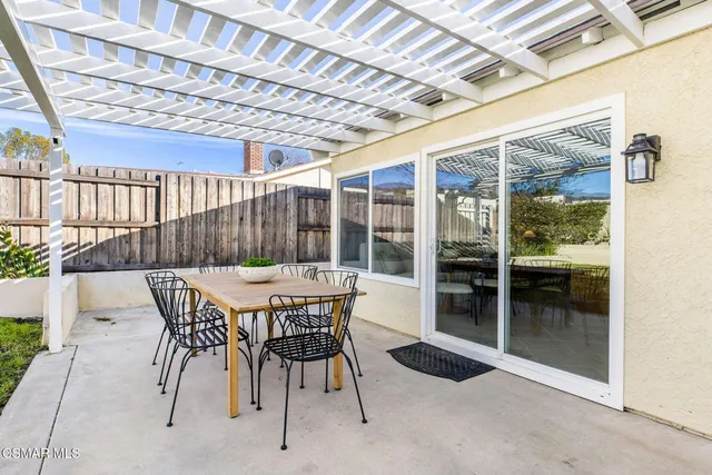 a patio with a table and chairs and potted plants