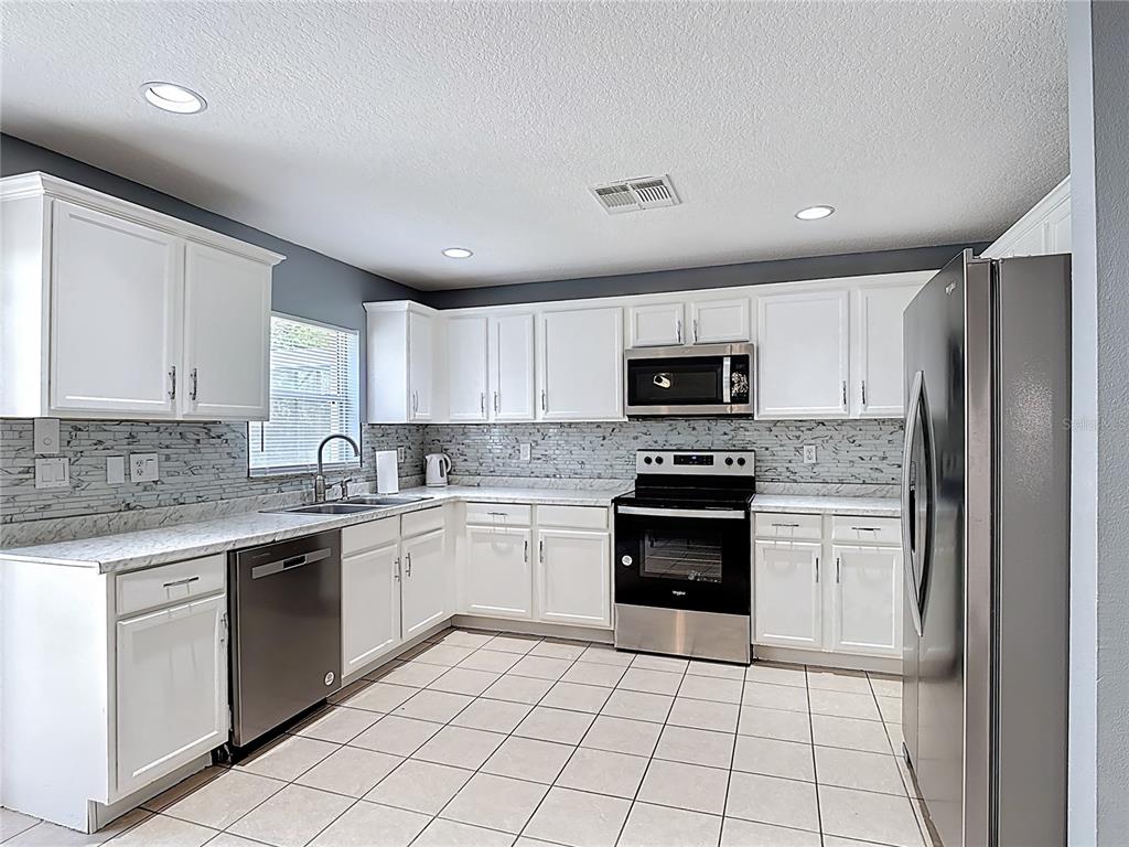 320 Mockingbird Road Davenport, FL 33896 - Photo 6 of 34 a kitchen with a sink a stove top oven and cabinets